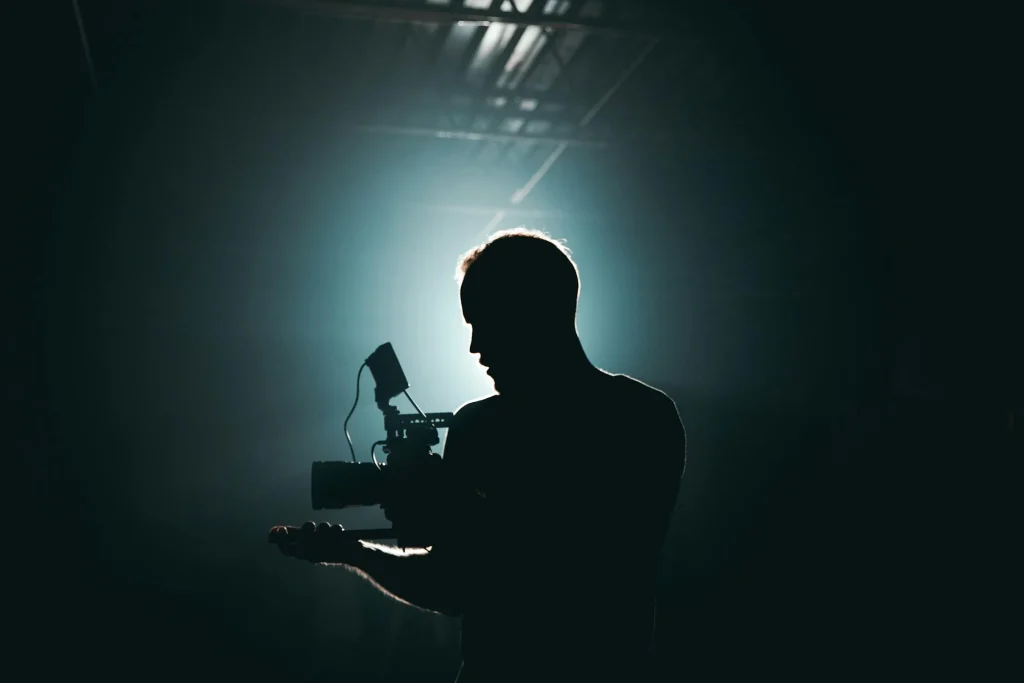 camera man in a dark room with an illuminated background